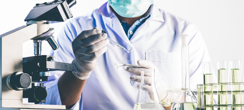 A researcher holding pipette and petri dish in a laboratory